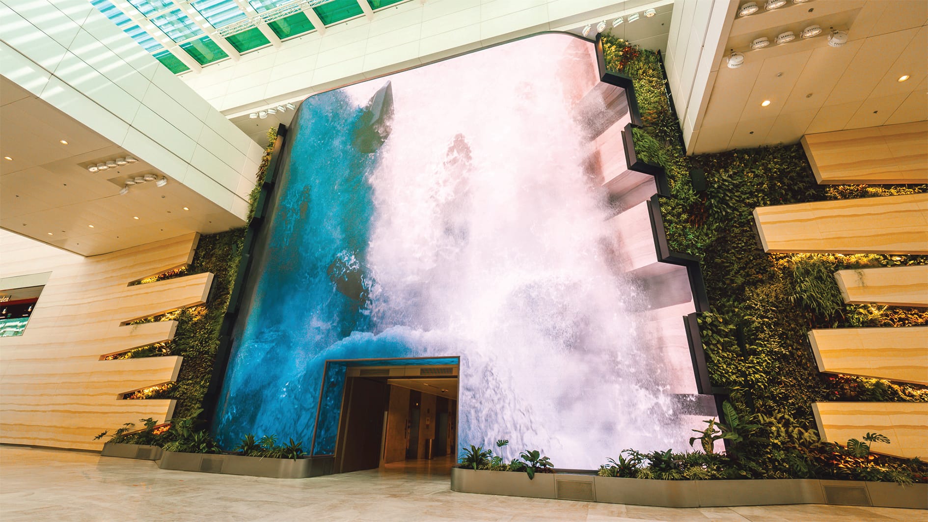 Indoor waterfall screen bordered by green walls at a building entrance.